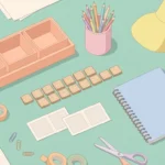 Pastel desk scene with blank wooden tiles, blank cards, a tray of empty boxes and pencils on a seafoam background.