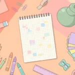 Pastel desk scene with colored pencils, crayons, grid paper and flash cards on a peach background.