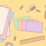 Pastel desk scene with paper, pencils, scissors, a glue stick, index cards and a ruler on butter yellow.