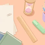 Pastel desk scene with paper, a sand timer, a ruler, colored pencils, a highlighter and books on peach.